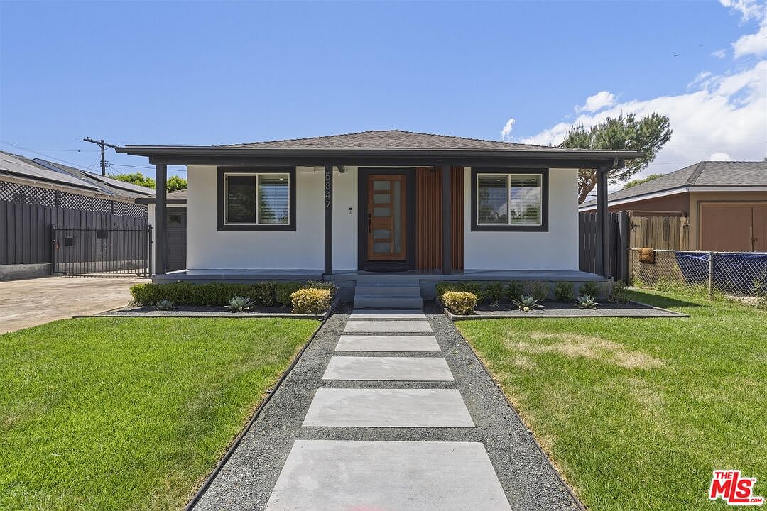 Front of 5847 Texhoma Avenue in daylight, white stucco with dark window trim, paver walkway, and clear blue sky